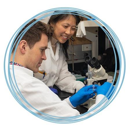 A faculty member assists a research student with setting up a microscope